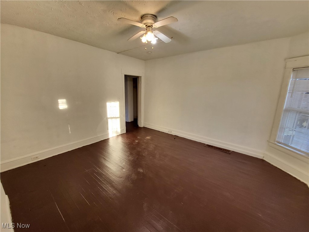Unfurnished room featuring dark wood-style floors and a ceiling fan