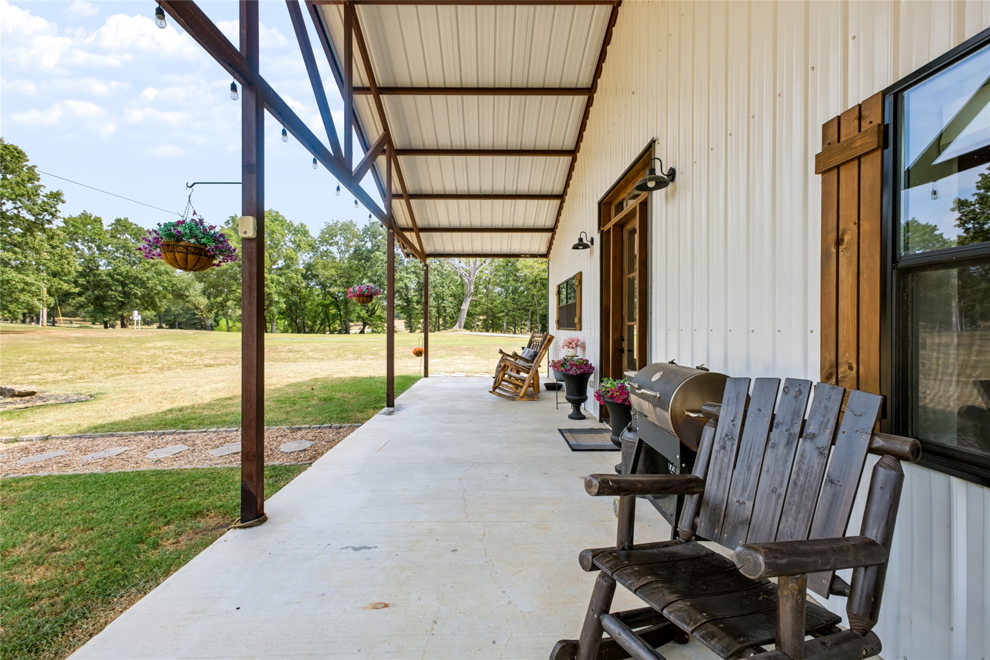 3607 South Half Bank Road Atoka, OK 74525 - Photo 49 of 82 Covered concrete porch with exposed beam ceiling, string lighting, and wood-finish shutters