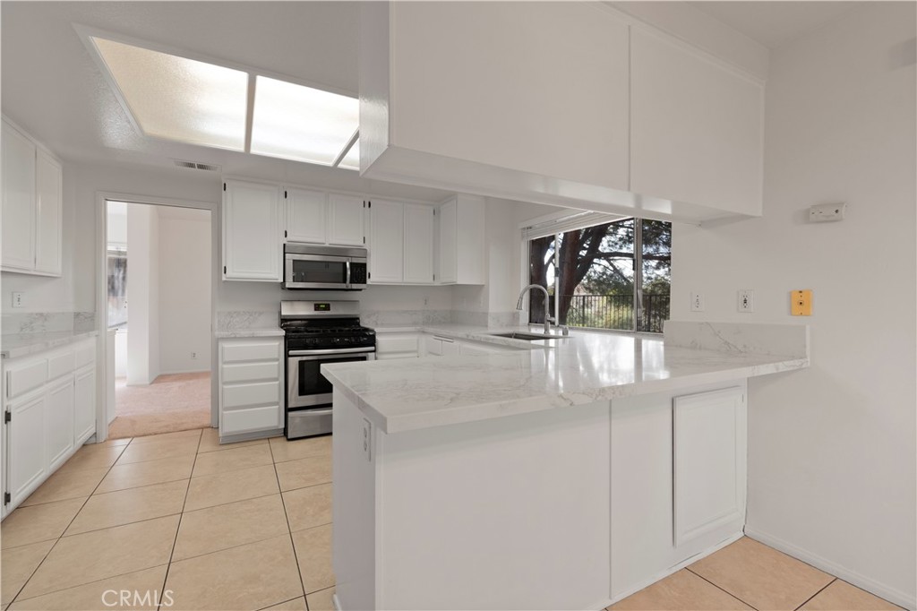 14 La Ramada Place Phillips Ranch, CA 91766 - Photo 25 of 61 a kitchen with stainless steel appliances kitchen island granite countertop a sink and cabinets