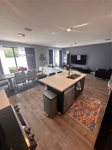 a large dining hall with stainless steel appliances granite countertop a stove top oven a dining table and chairs with wooden floor