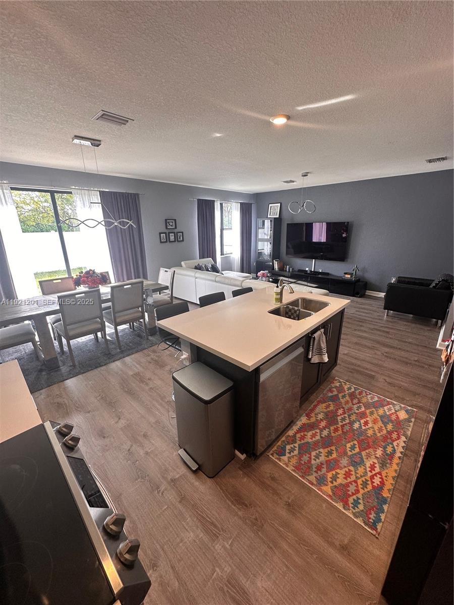 3378 West 100th Terrace, Unit 3378 Hialeah, FL 33018 - Photo 18 of 41 a large dining hall with stainless steel appliances granite countertop a stove top oven a dining table and chairs with wooden floor