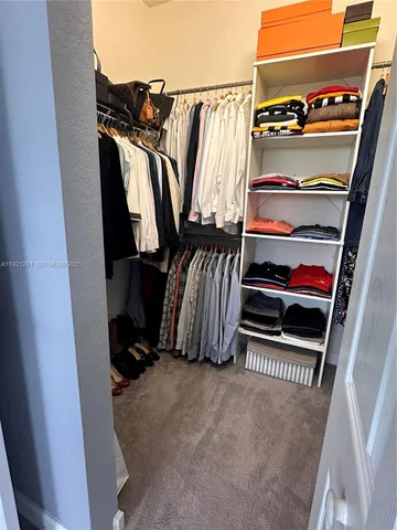 a view of walk in closet with clothes and shoes