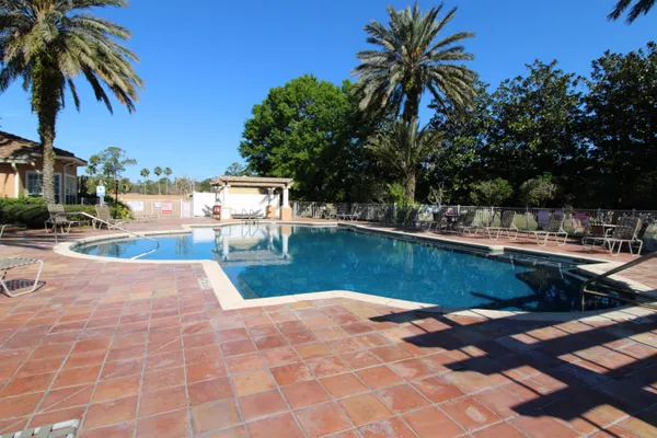 a view of a swimming pool with chair and table of the patio