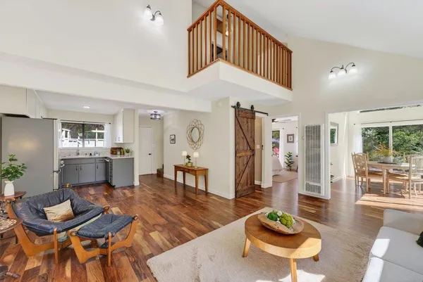 a living room with furniture and a dining table with wooden floor