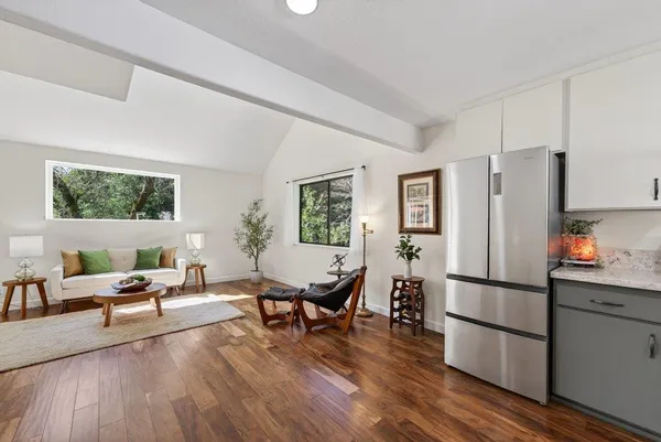 a living room with furniture wooden floor and a refrigerator
