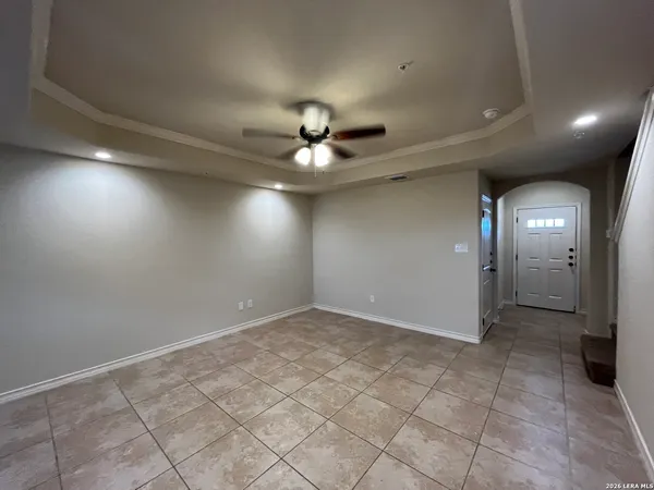 an empty room with fan and way to kitchen