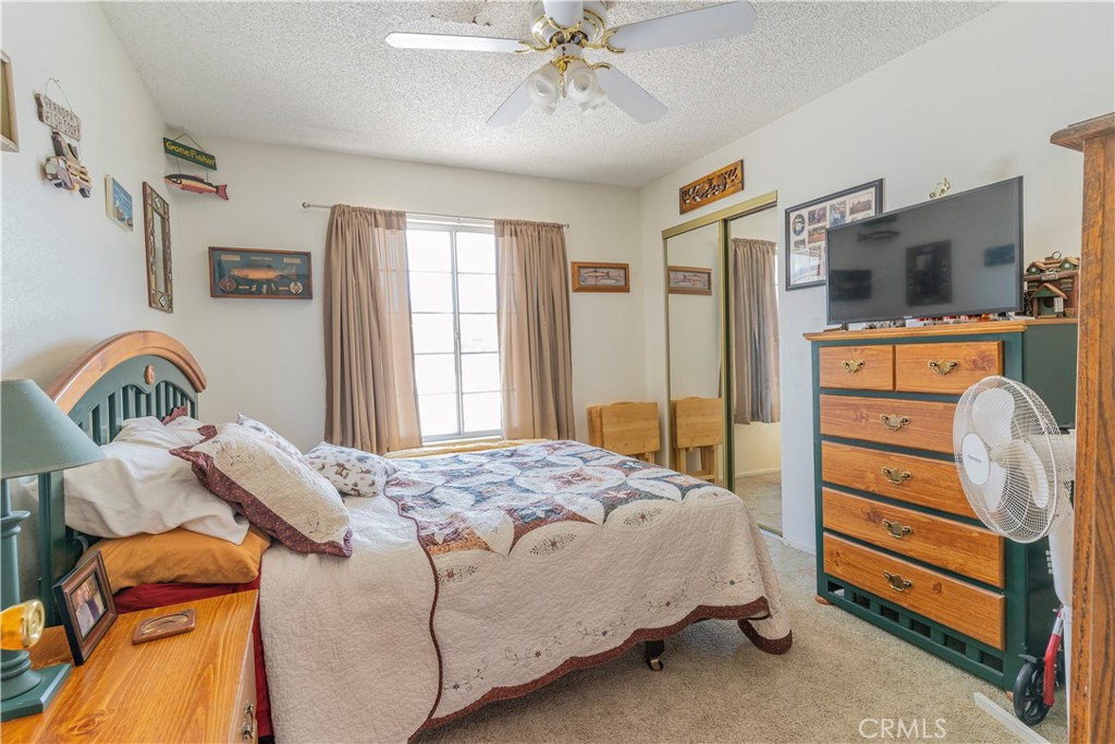 17516 Olive Street Hesperia, CA 92345 - Photo 17 of 32 a bedroom with a bed and a flat tv screen