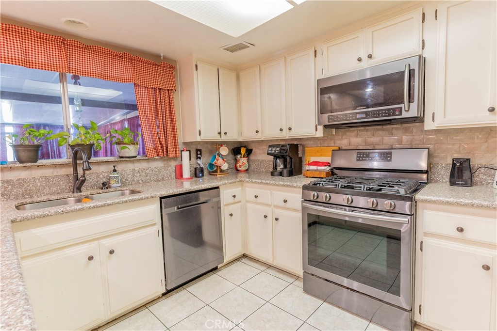 17516 Olive Street Hesperia, CA 92345 - Photo 10 of 32 a kitchen with stainless steel appliances granite countertop a sink a stove and a microwave
