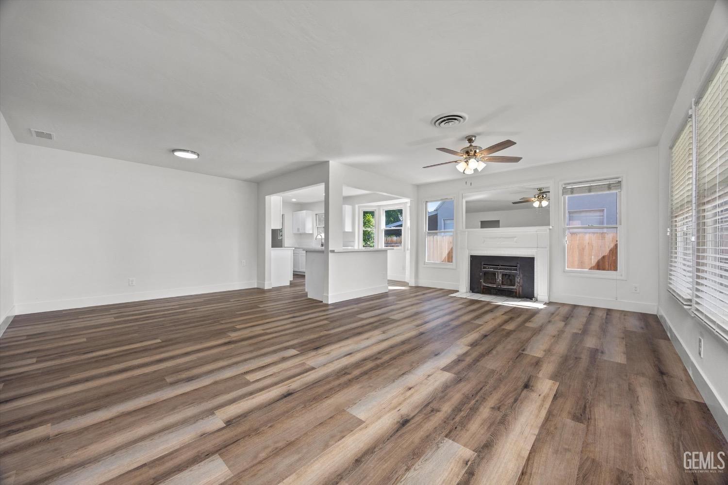 Undisclosed Address Bakersfield, CA 93301 - Photo 7 of 33 an empty room with fireplace wooden floor chandelier and windows