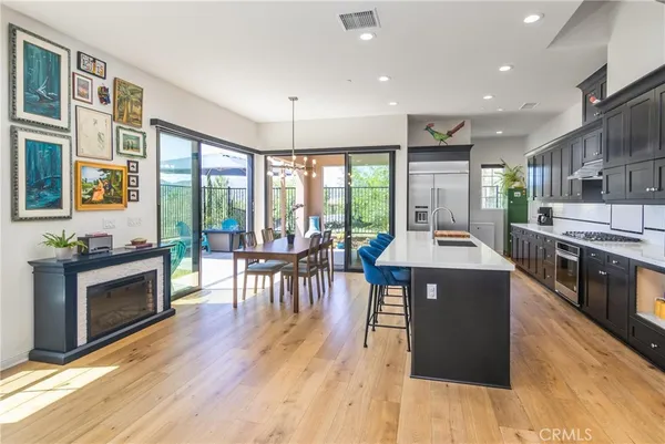 a kitchen with stainless steel appliances granite countertop a stove top oven a refrigerator a dining table and chairs with wooden floor