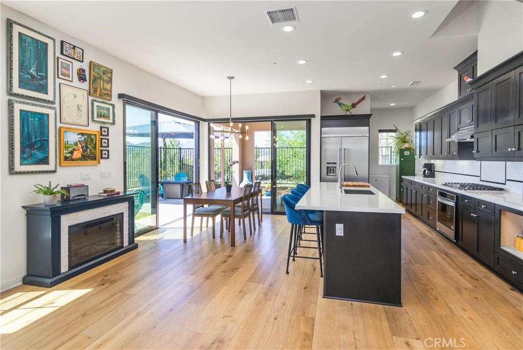 20724 Beech Circle Porter Ranch, CA 91326 - Photo 5 of 27 a kitchen with stainless steel appliances granite countertop a stove top oven a refrigerator a dining table and chairs with wooden floor