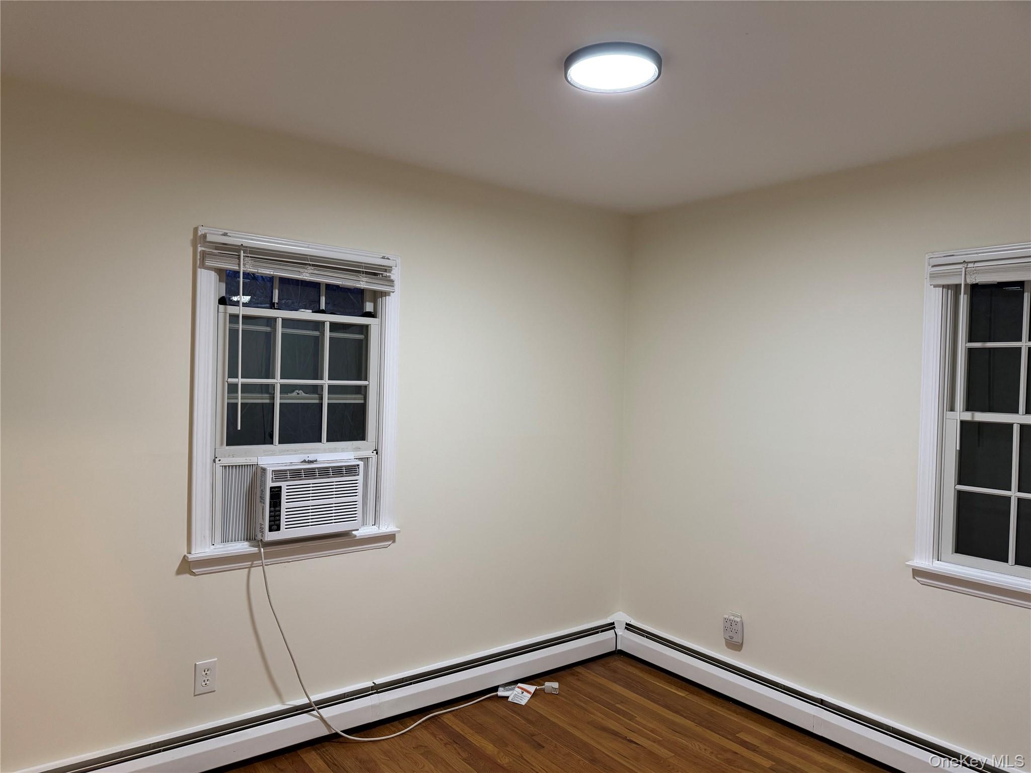 23 Jerome Road Syosset, NY 11791 - Photo 11 of 12 Empty room with a baseboard heating unit, dark wood-type flooring, and cooling unit