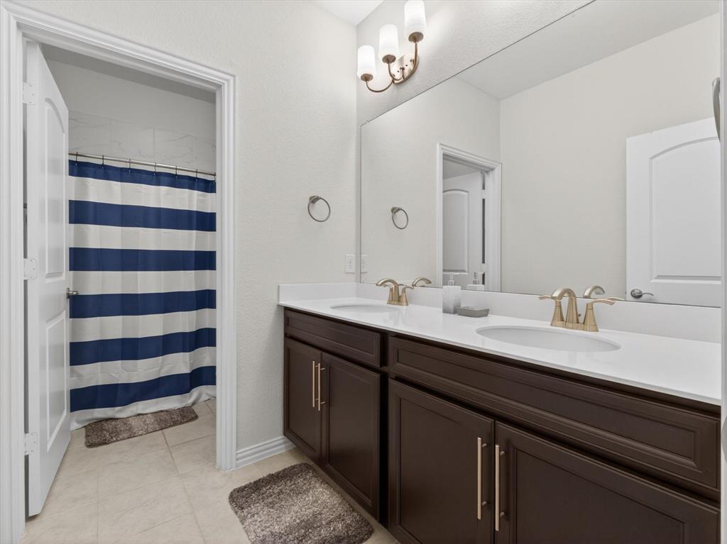 636 Corner Post Path Celina, TX 75009 - Photo 29 of 40 Dual vanity with white countertops, dark wood-finish cabinetry, and gold-tone fixtures