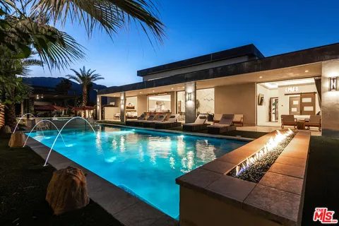 a view of a swimming pool with a patio and couches chairs