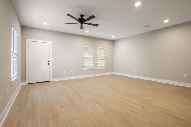 an empty room with ceiling fan and windows