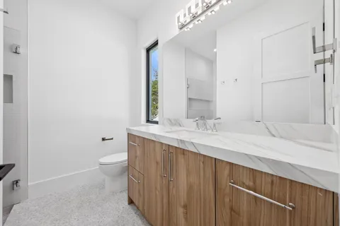 a bathroom with a granite countertop sink mirror vanity and toilet