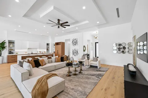 a living room with furniture kitchen view and a chandelier