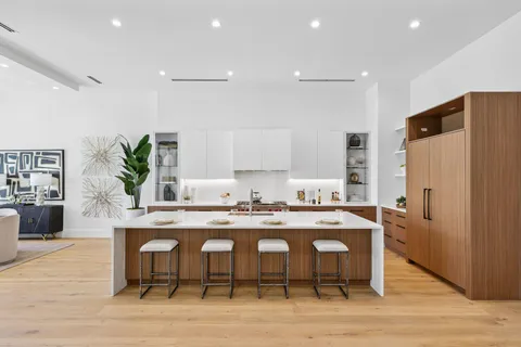 a kitchen with stainless steel appliances granite countertop a dining table chairs stove refrigerator and cabinets