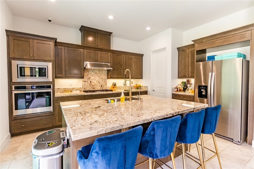 19047 Bension Drive Saugus, CA 91350 - Photo 19 of 72 Granite countertops and backsplash. Kitchen island with sink and upgraded faucet and filtered water dispenser.