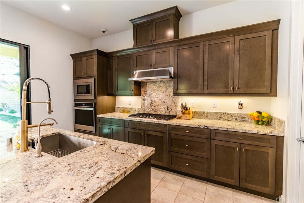 19047 Bension Drive Saugus, CA 91350 - Photo 20 of 72 Granite countertops and backsplash. Kitchen island with sink and upgraded faucet and filtered water dispenser.