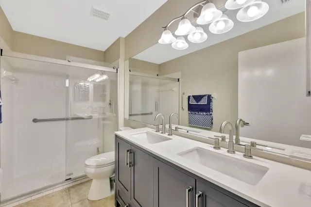 a bathroom with a sink a toilet a mirror and shower