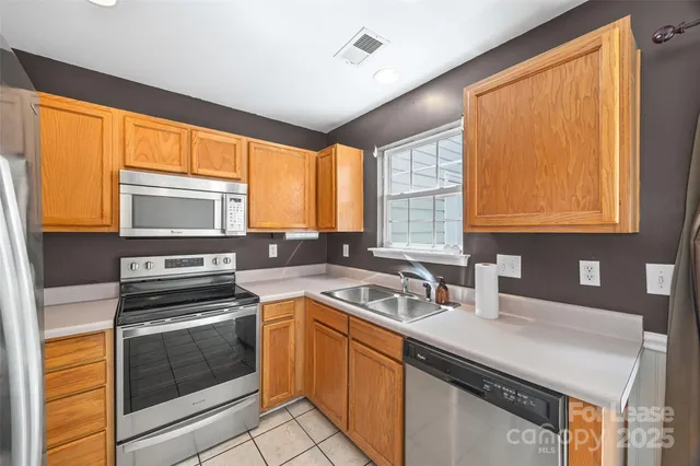 a kitchen with stainless steel appliances granite countertop a refrigerator a stove top oven a sink and dishwasher