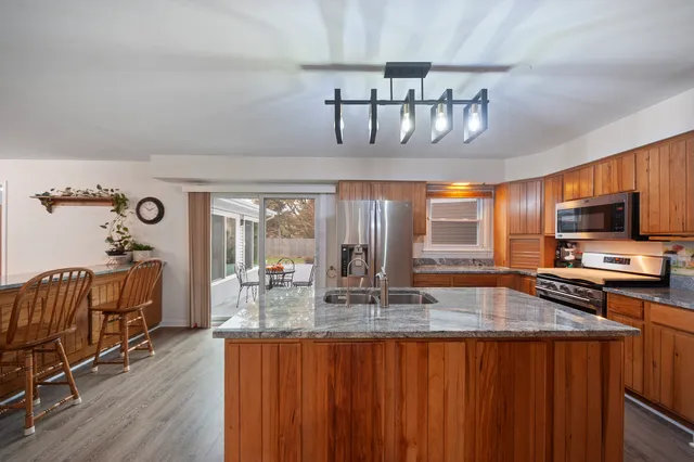 a kitchen with stainless steel appliances granite countertop a sink dishwasher and cabinets with wooden floor