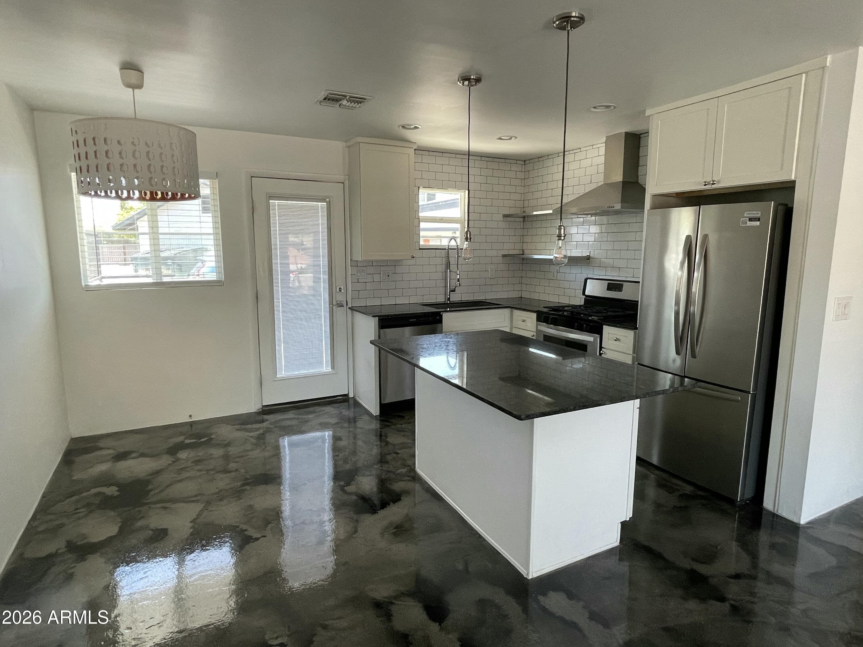 a kitchen with stainless steel appliances granite countertop a sink and a refrigerator