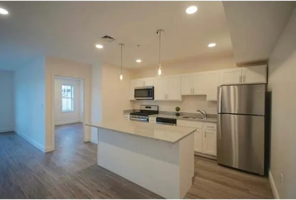 a view of a kitchen with kitchen island a sink wooden floor and stainless steel appliances