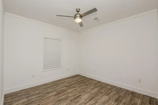 an empty room with wooden floor and ceiling fan