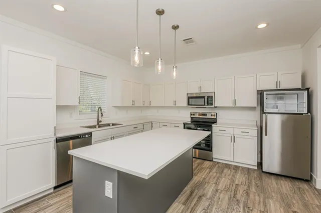 a kitchen with a sink a stove a refrigerator and white cabinets