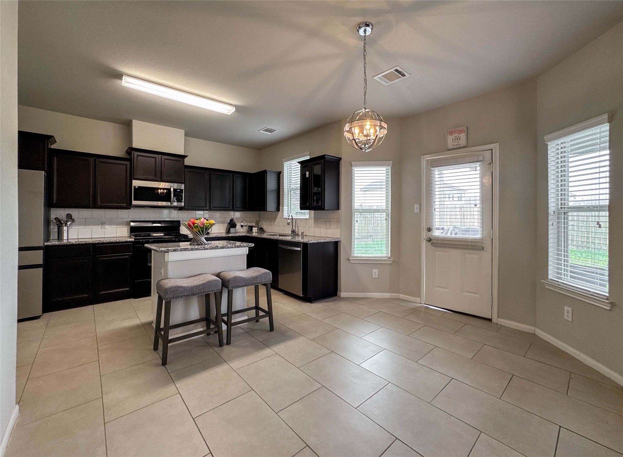 2 Eagle Lake Court Manvel, TX 77578 - Photo 5 of 38 a kitchen with stainless steel appliances granite countertop a stove top oven a refrigerator a sink dishwasher a dining table and chairs with wooden floor