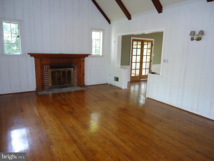 10407 Rodney Road Silver Spring, MD 20903 - Photo 9 of 9 an empty room with wooden floor fireplace and windows