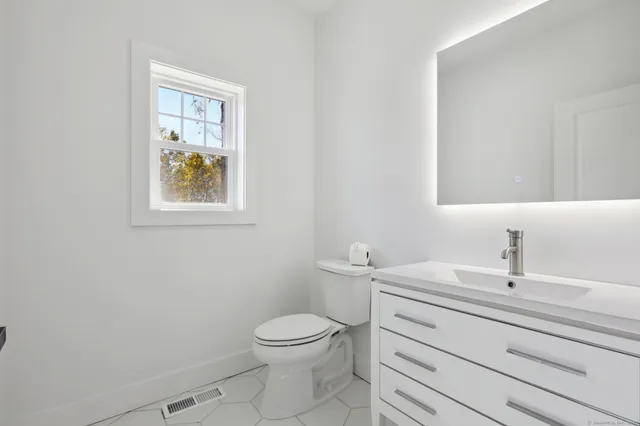 a bathroom with a toilet sink vanity and mirror