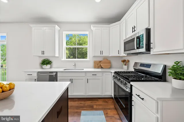 a kitchen with stainless steel appliances white cabinets and a stove top oven