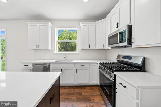 a kitchen with stainless steel appliances granite countertop a stove a sink and a microwave