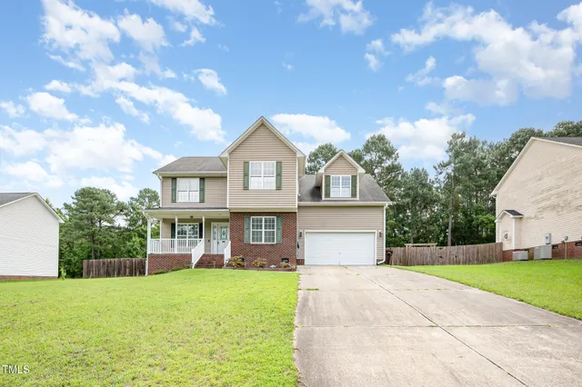 a front view of a house with yard and green space