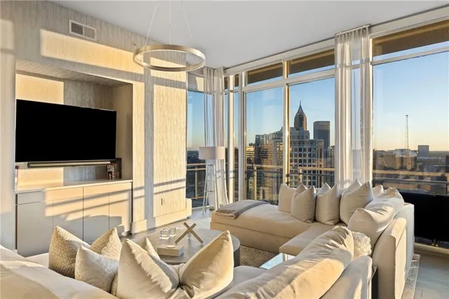 a living room with furniture a flat screen tv and a floor to ceiling window
