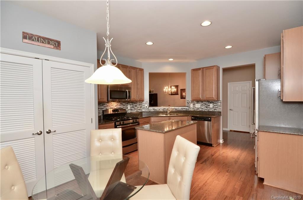 113 Inlet Point Drive Tega Cay, SC 29708 - Photo 10 of 42 a kitchen with stainless steel appliances granite countertop a stove refrigerator a sink dishwasher a dining table and chairs with wooden floor