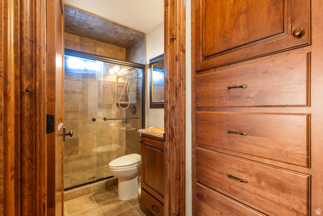 892 Cambridge Drive St. George, UT 84770 - Photo 18 of 65 Bathroom featuring a glass-enclosed shower with tile surround, a single vanity with stone countertop, and wood-finish storage cabinetry