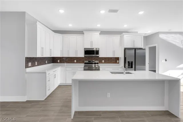 a kitchen with kitchen island granite countertop a sink a stove a microwave and cabinets