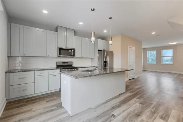 a kitchen with stainless steel appliances granite countertop a stove a sink and white cabinets