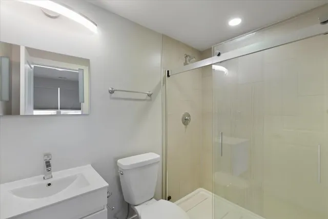 a bathroom with a toilet sink vanity and shower