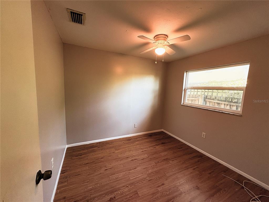 11333 Walsingham Road Largo, FL 33778 - Photo 20 of 34 a view of an empty room with wooden floor and a fan