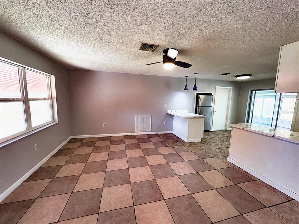 11333 Walsingham Road Largo, FL 33778 - Photo 6 of 34 a living room with a black white checkered floor with a gaming machine and dining table