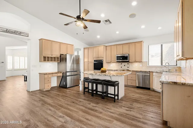 a kitchen with stainless steel appliances a refrigerator a stove a sink cabinets and wooden floor