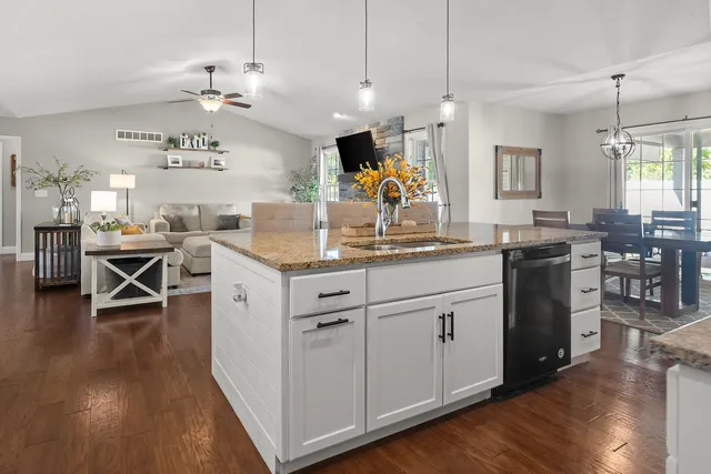 a kitchen with stainless steel appliances kitchen island granite countertop a table chairs and a refrigerator