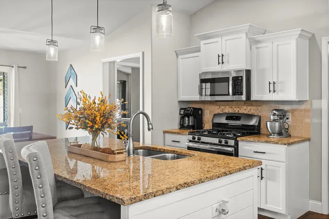 a kitchen with granite countertop white cabinets and stainless steel appliances