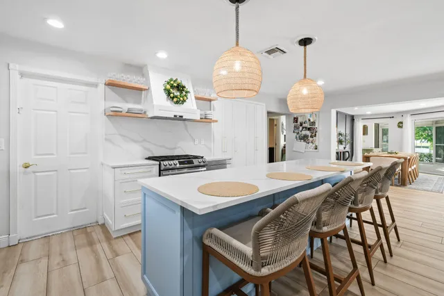 a large kitchen with kitchen island a stove a sink dishwasher a dining table and chairs with wooden floor