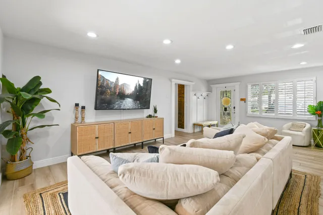 a kitchen with kitchen island stainless steel appliances a dining table chairs sink and wooden floor